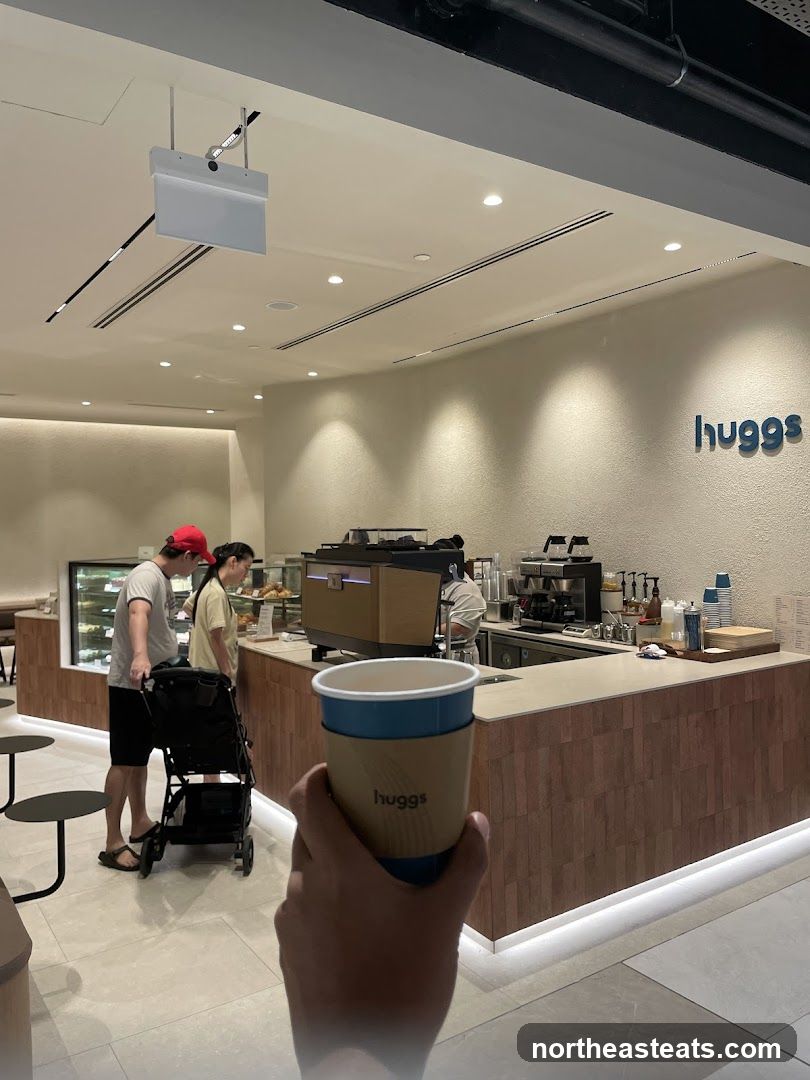Coffee shop interior with customers and a hand holding a coffee cup