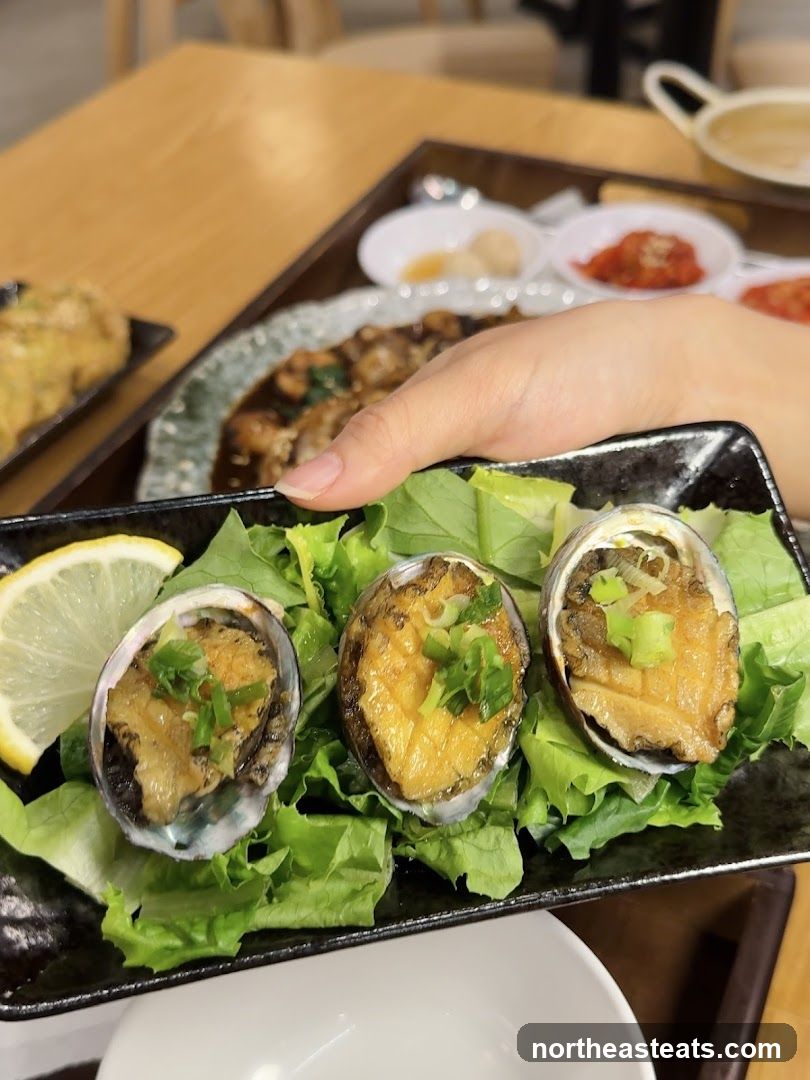 Three cooked abalone shells with garnish