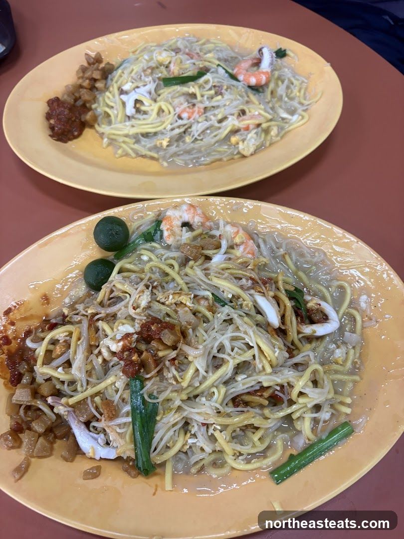 Two plates of noodles with shrimp and squid