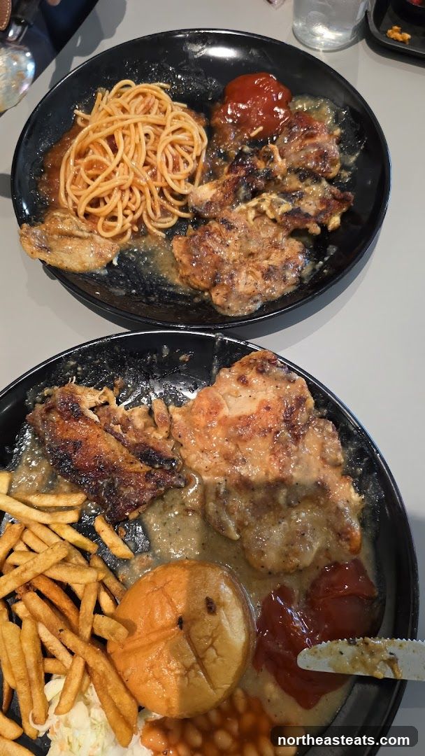 Two plates of grilled chicken with sides