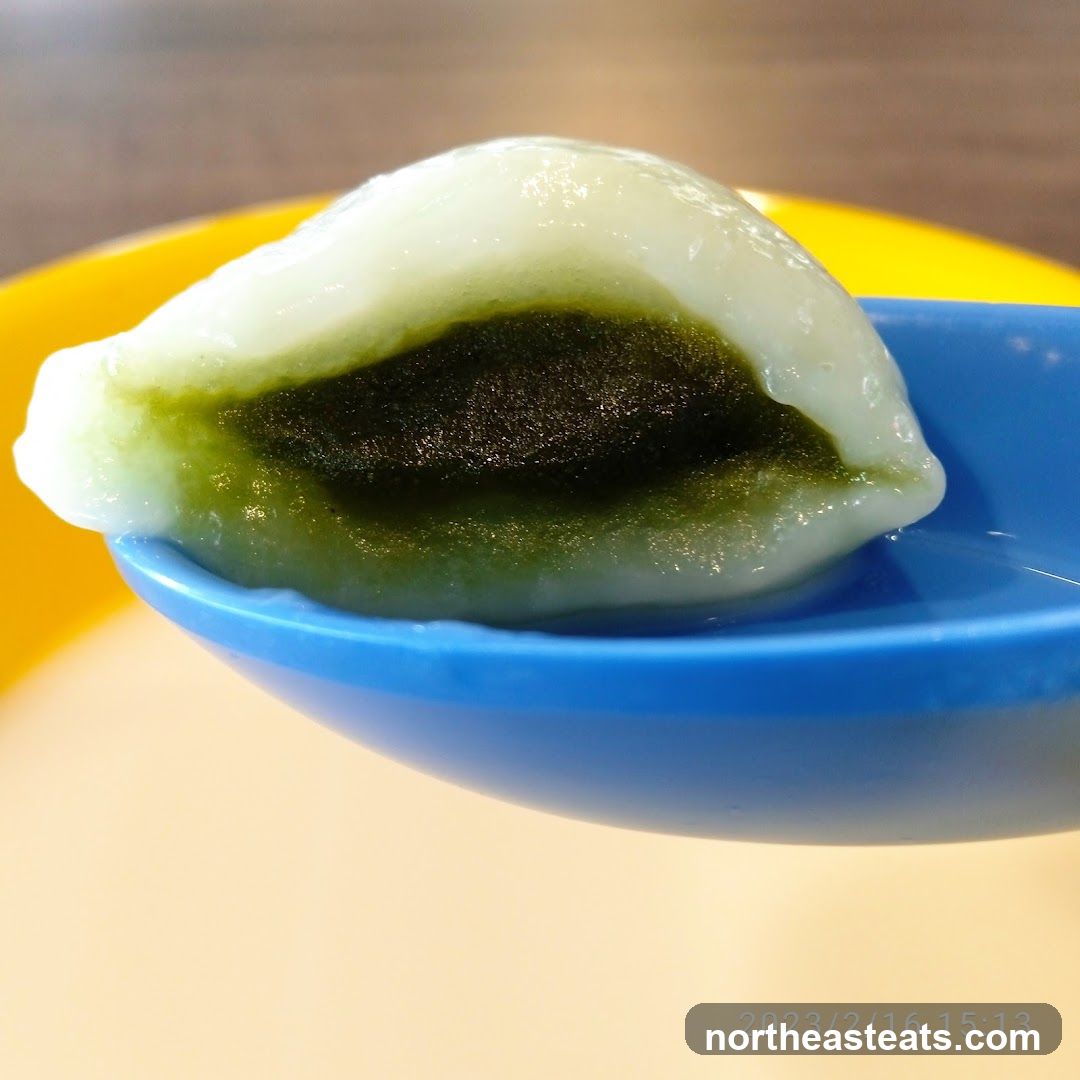 Close-up of a green mochi ball on a blue spoon