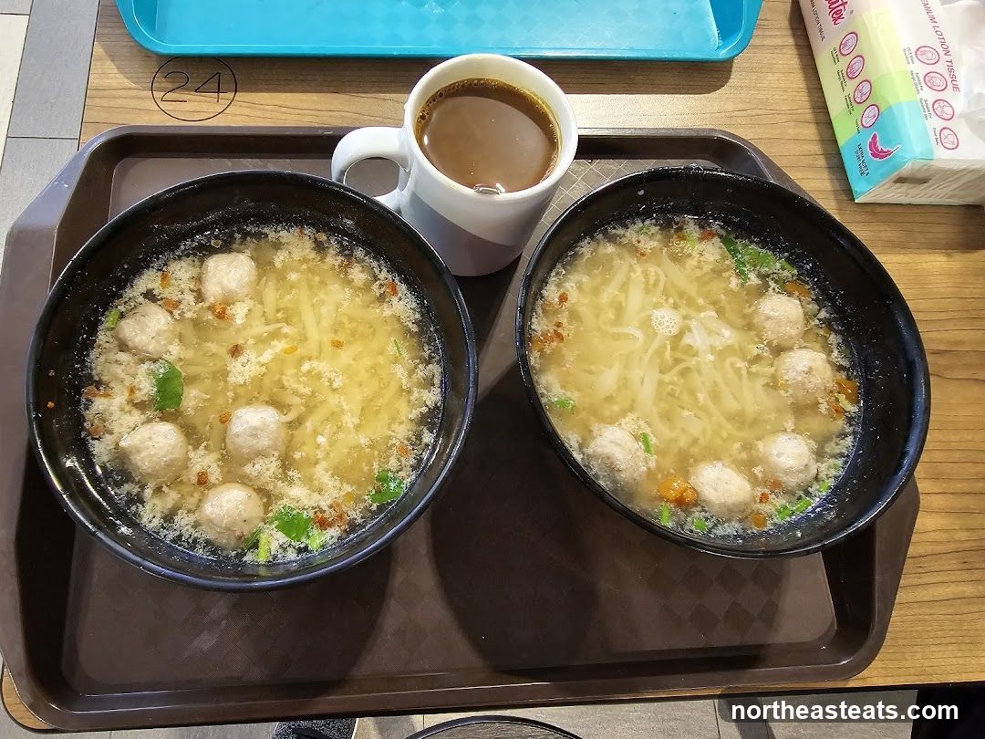 Two bowls of noodle soup with meatballs and a cup of coffee