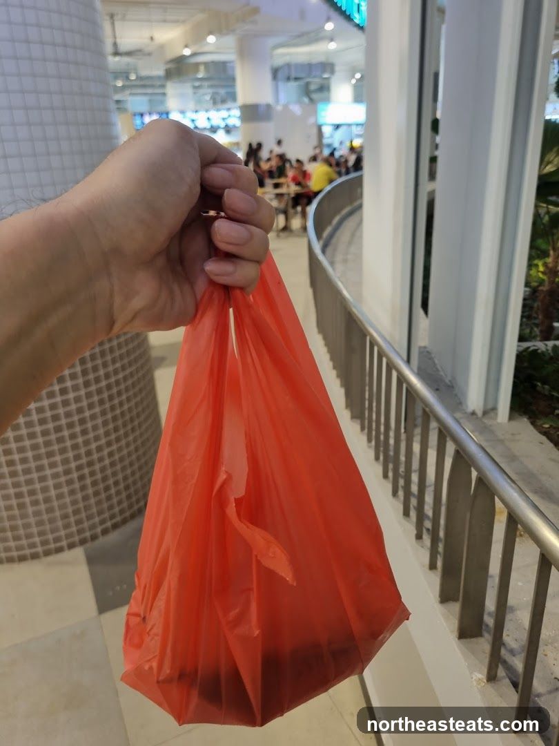 Hand holding a red plastic bag with food