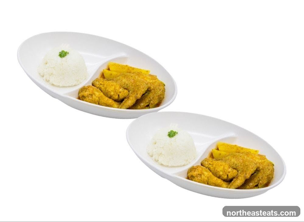 Two plates of curry chicken wings with rice and fries