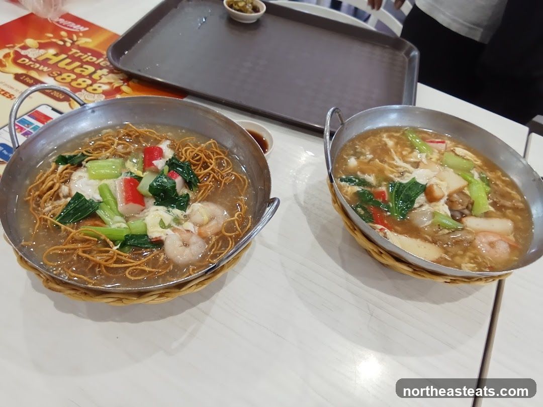 Two bowls of noodles with seafood and vegetables