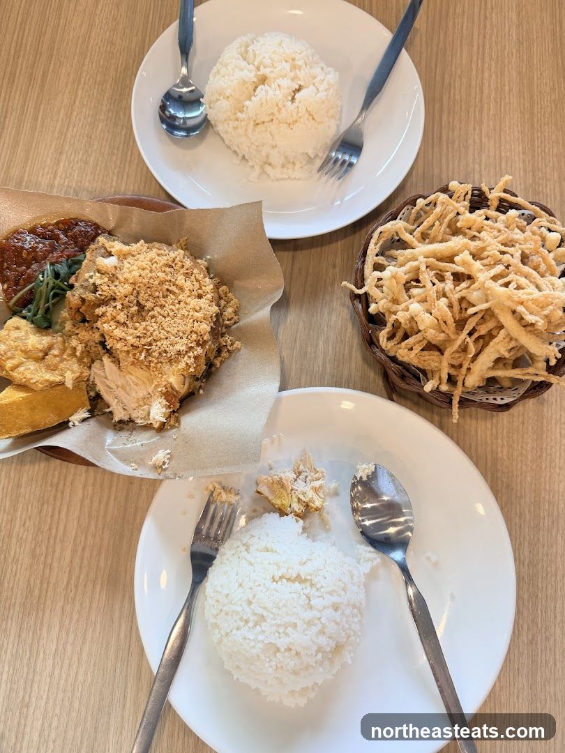 Two plates of rice with fried chicken and a basket of fried mushrooms
