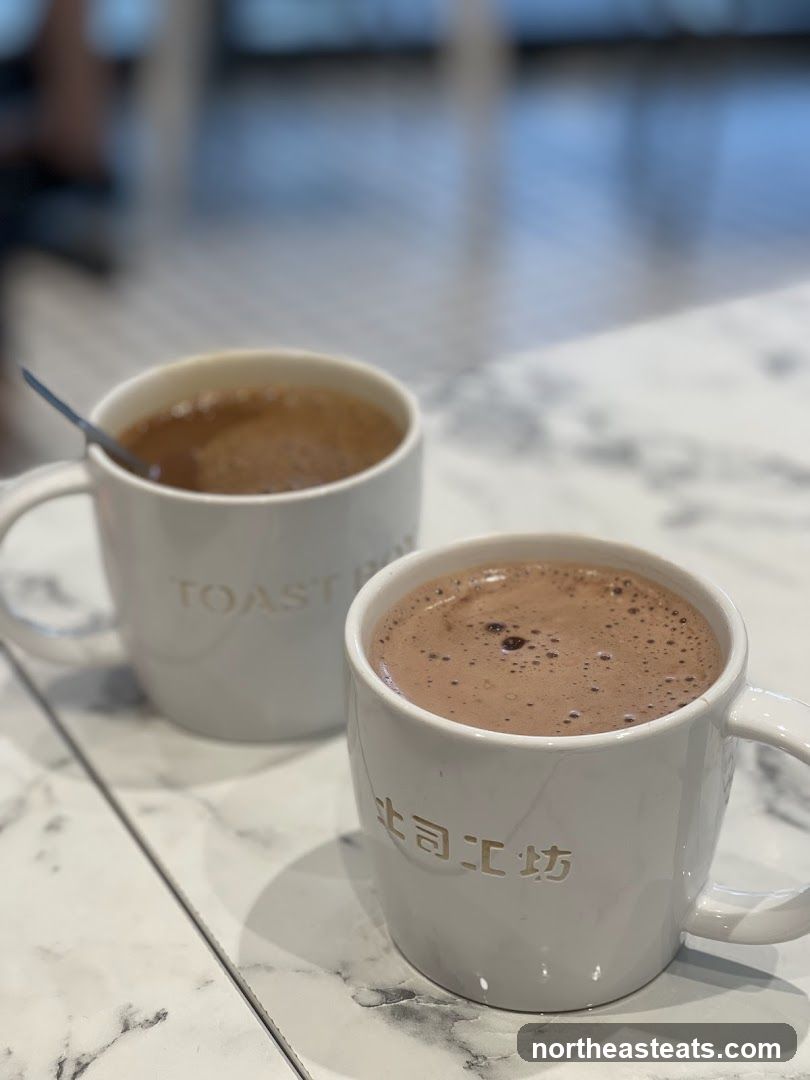 Two mugs of hot beverages on a marble table