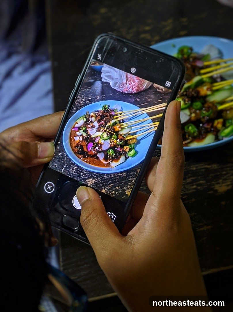 Person taking a photo of satay