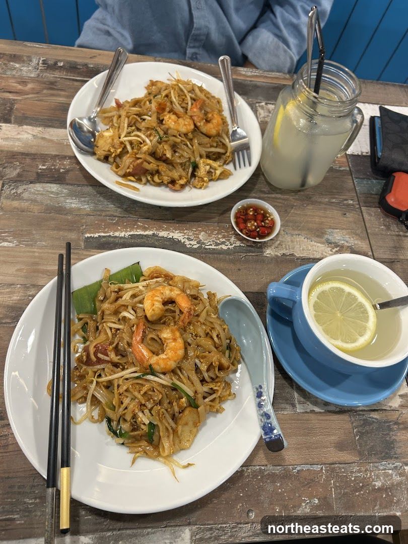 Two plates of Pad Thai with shrimp and a drink