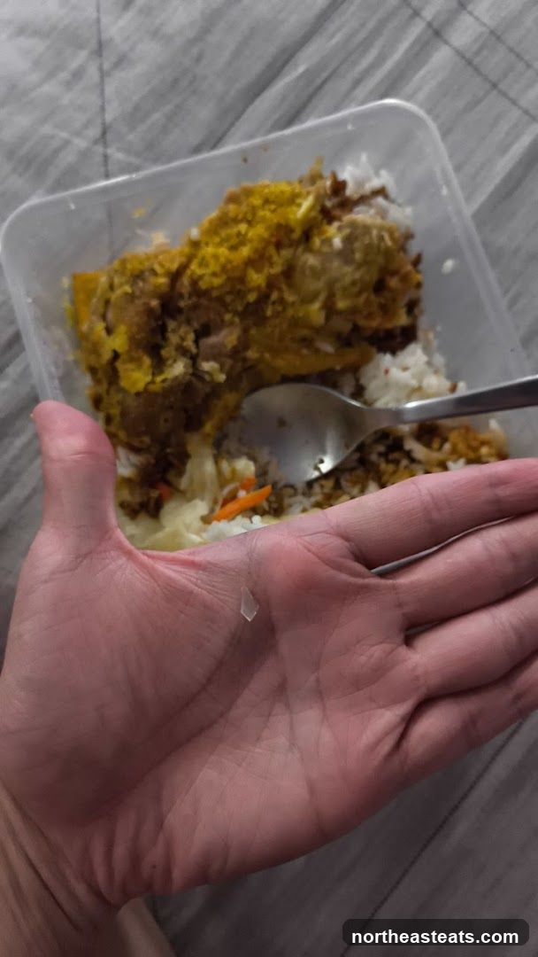 Hand holding a piece of plastic over a meal