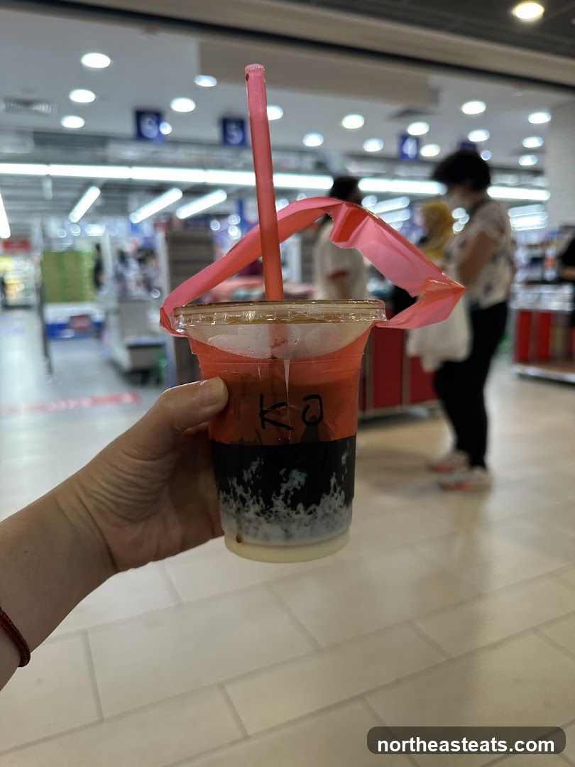 Hand holding a drink with a pink straw and ribbon