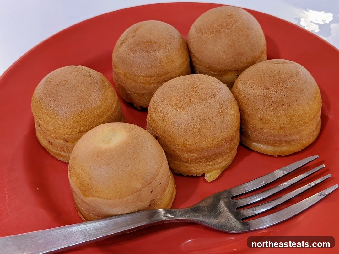 Six small cakes on a red plate with a fork