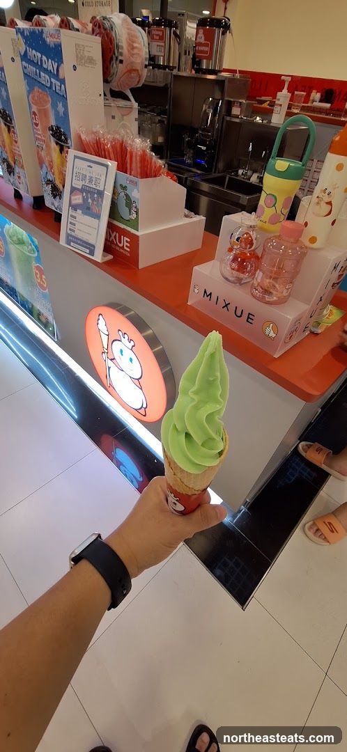 Hand holding green soft serve ice cream cone