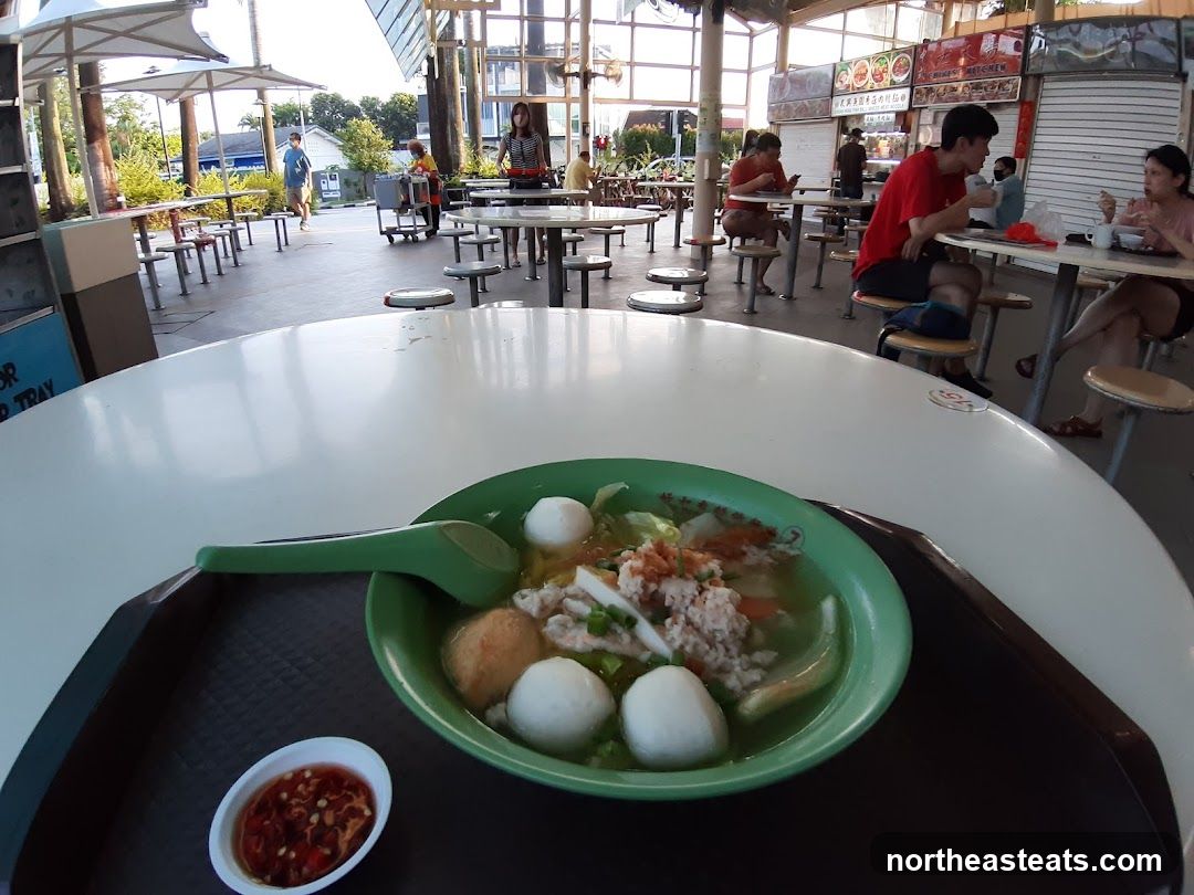 Food court with diners and a bowl of soup