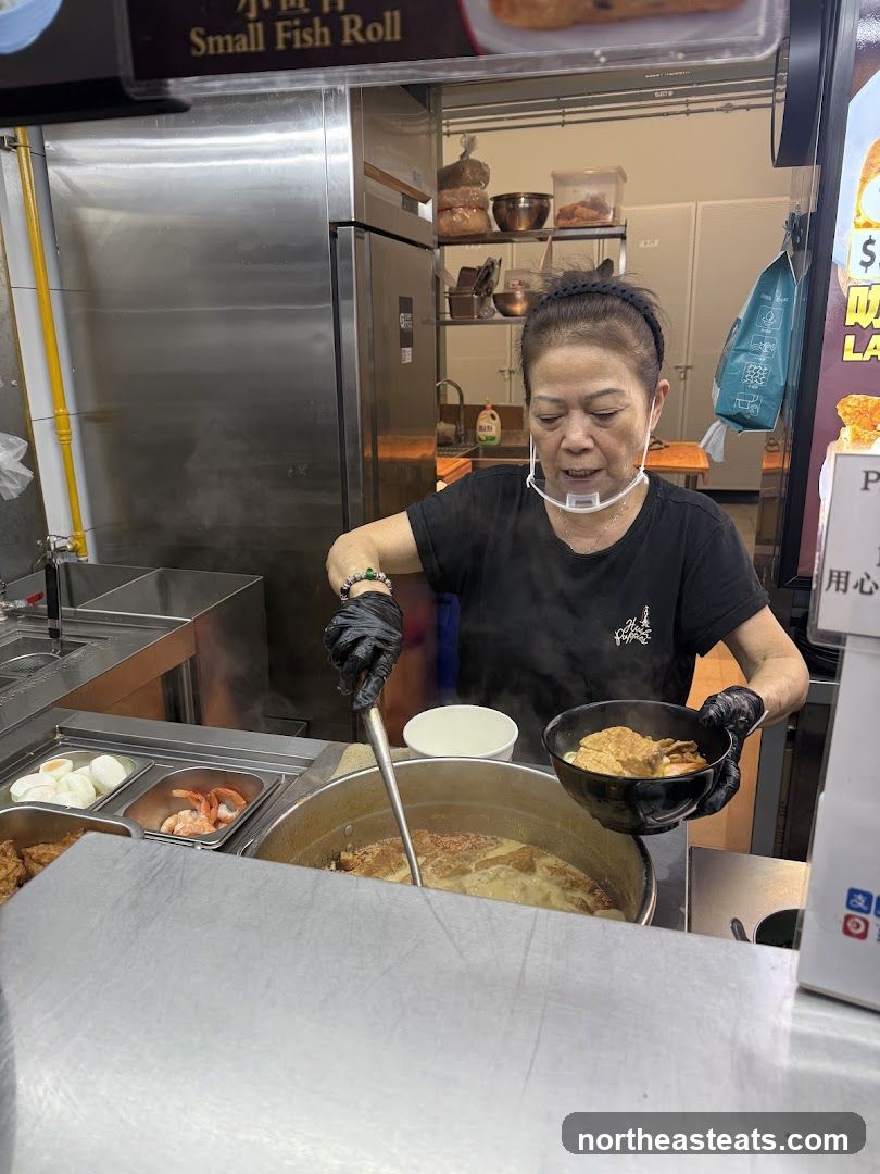 Food stall vendor serving a bowl of noodles