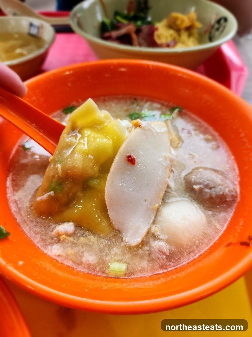 Close-up of a bowl of soup with dumplings and fish cakes