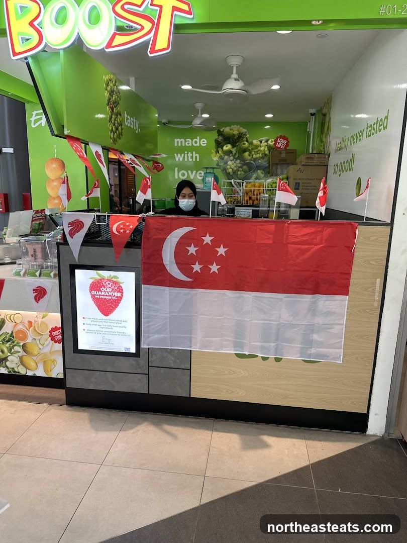 A Boost Juice Bar storefront decorated with Singaporean flags and banners. A staff member wearing a mask is visible behind the counter. The store's logo "BOOST" is prominently displayed above the entrance.