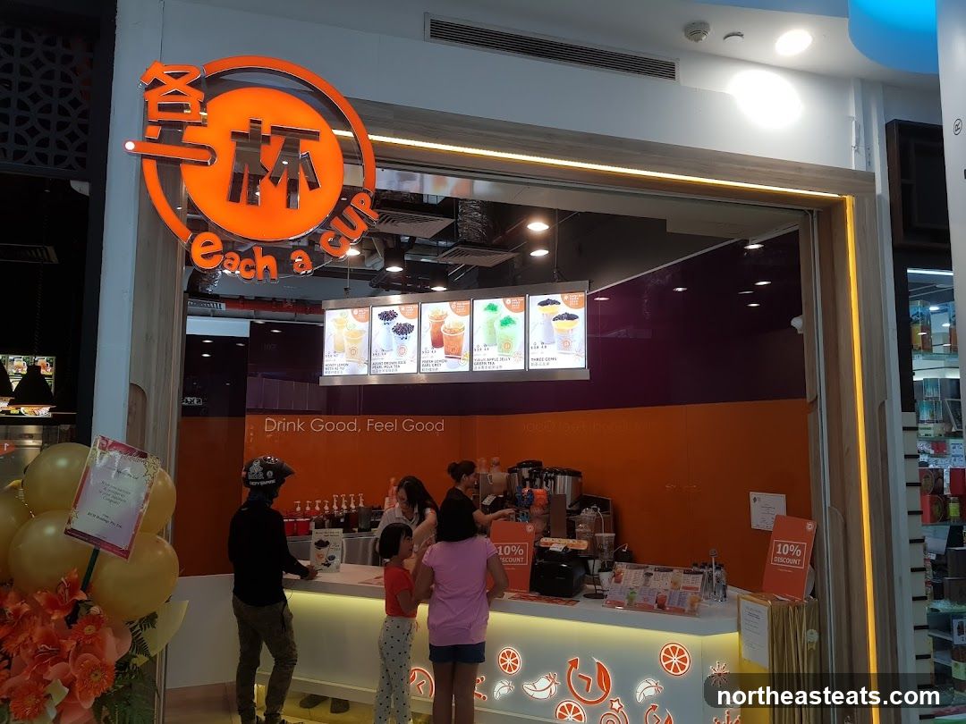 A brightly lit bubble tea shop with an orange and white color scheme. The shop's logo,