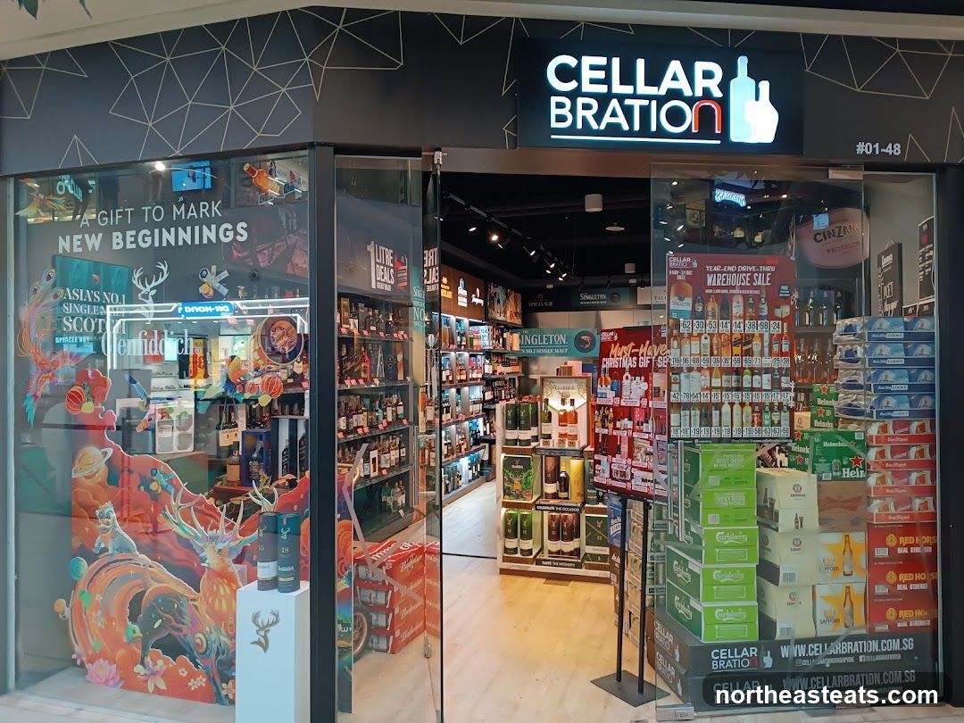The exterior of a liquor store with a large glass window displaying various bottles of alcohol, promotional posters, and branded merchandise. The store's name,