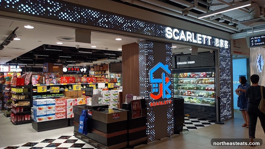 A view of the Scarlett supermarket entrance, showcasing its signage and a chilled food display. The store features a modern design with illuminated dots on the facade. Shelves stocked with various products are visible in the background.