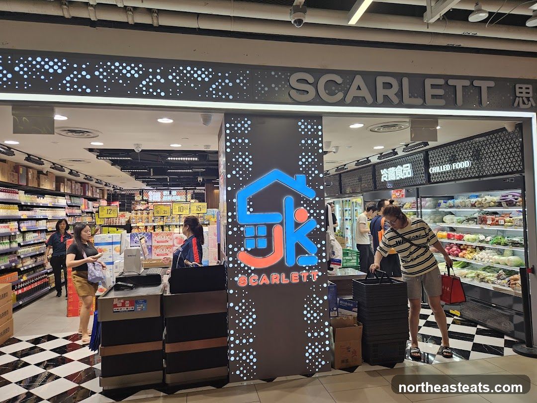 The entrance to a supermarket named Scarlett. The store has a modern facade with a prominent sign displaying the name