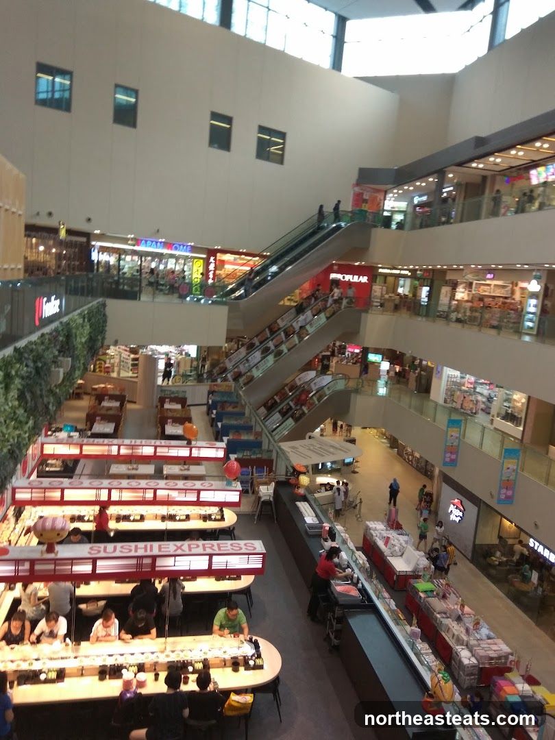 Busy shopping mall interior with escalators and various shops