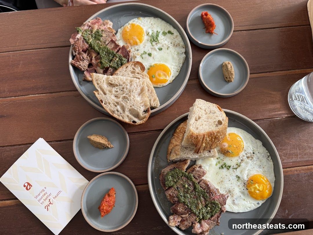 Two plates of steak and eggs with bread