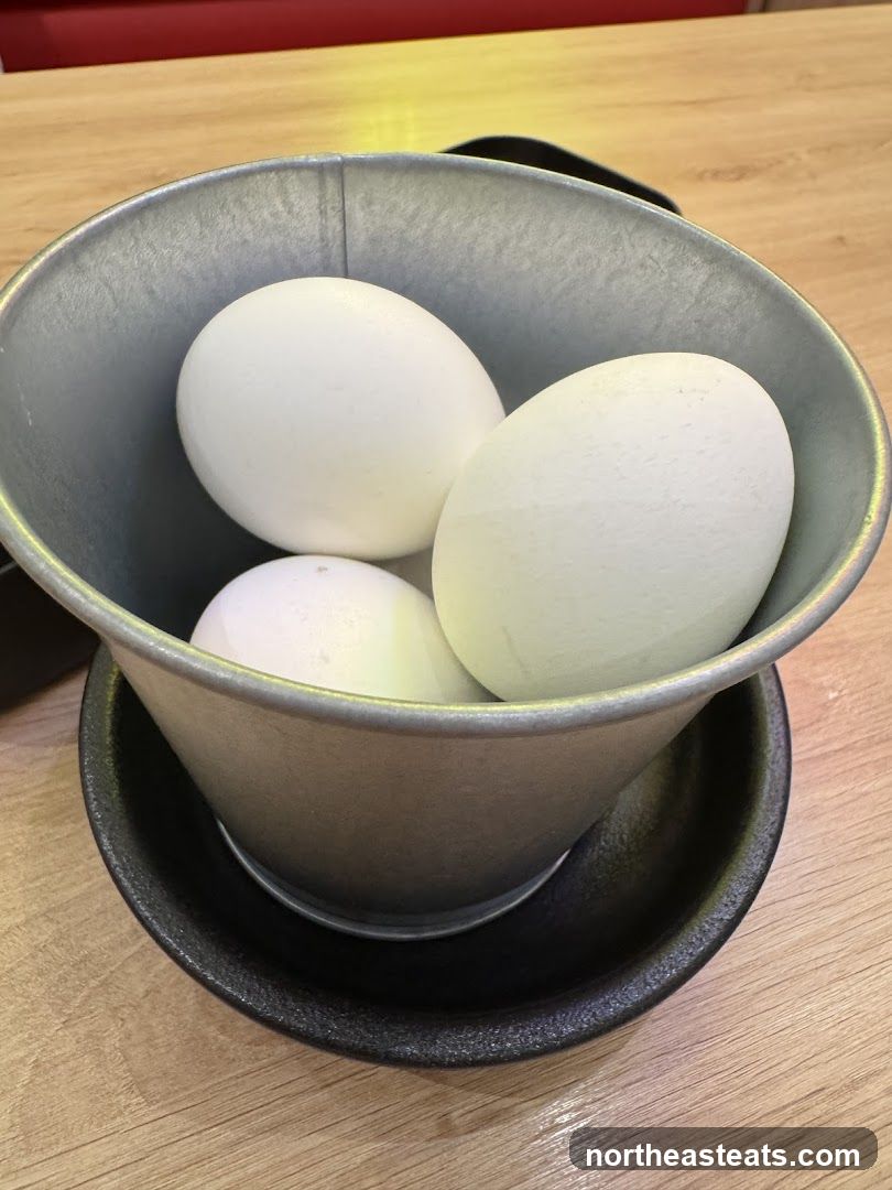 Three white eggs in a metal bucket