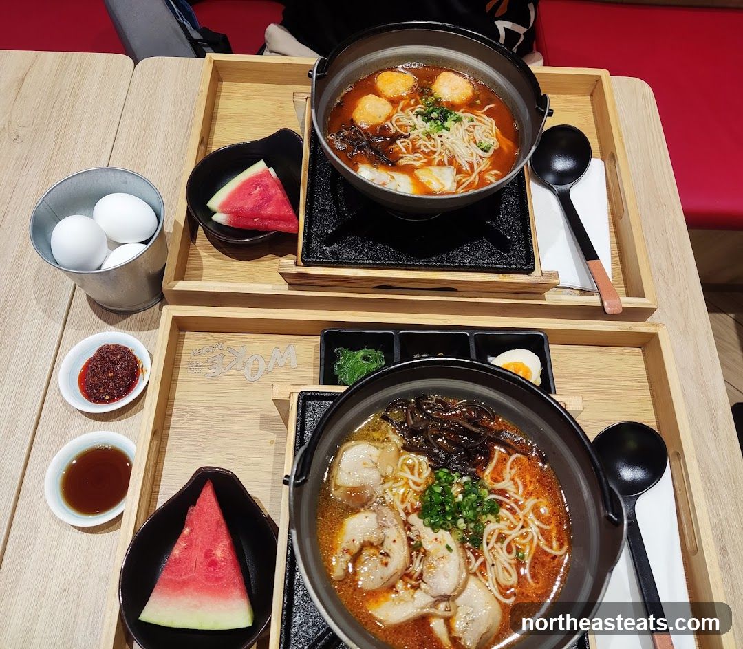 Two bowls of ramen with side dishes