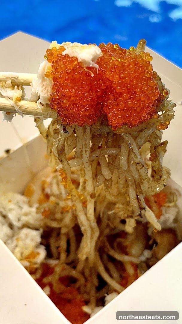 Chopsticks holding noodles with crab and roe