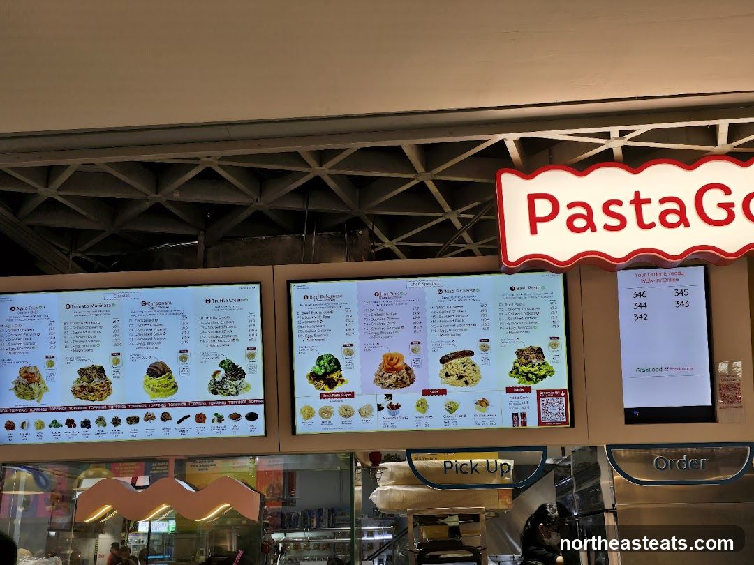 A digital menu board displaying various pasta dishes and toppings.