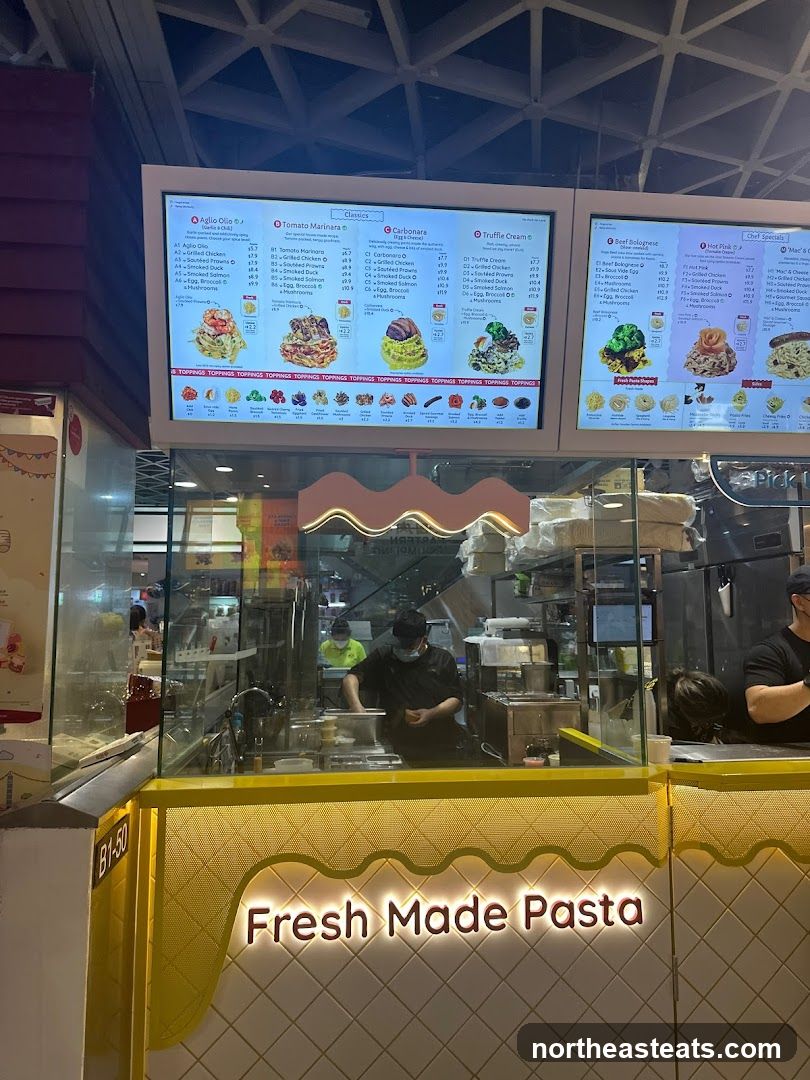 A digital menu board displaying various pasta dishes and toppings.