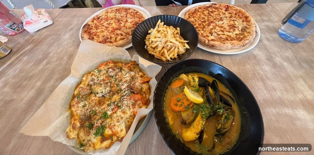 Table with Pizzas, Fries, and Seafood Stew