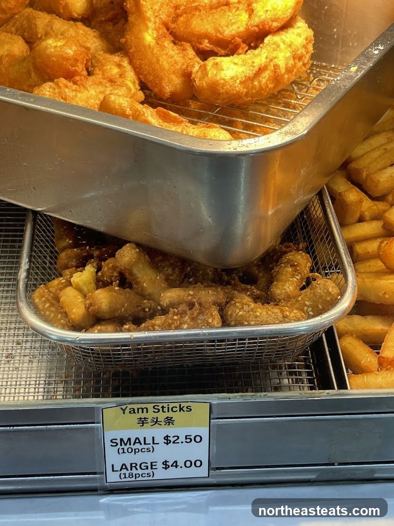 A close-up view of fried yam sticks displayed in a metal basket, with a price label below.