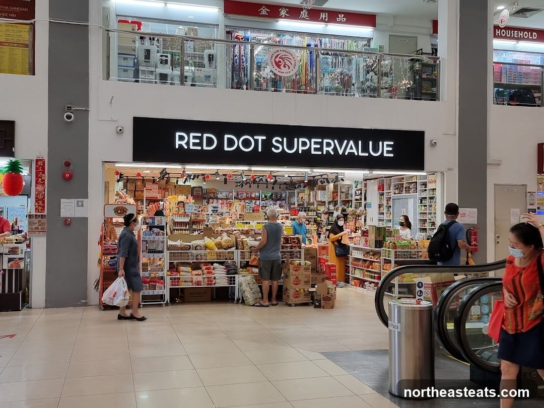 The exterior of a store called Red Dot Supervalue. The store is filled with shelves of products. People are seen browsing and shopping inside and outside the store.