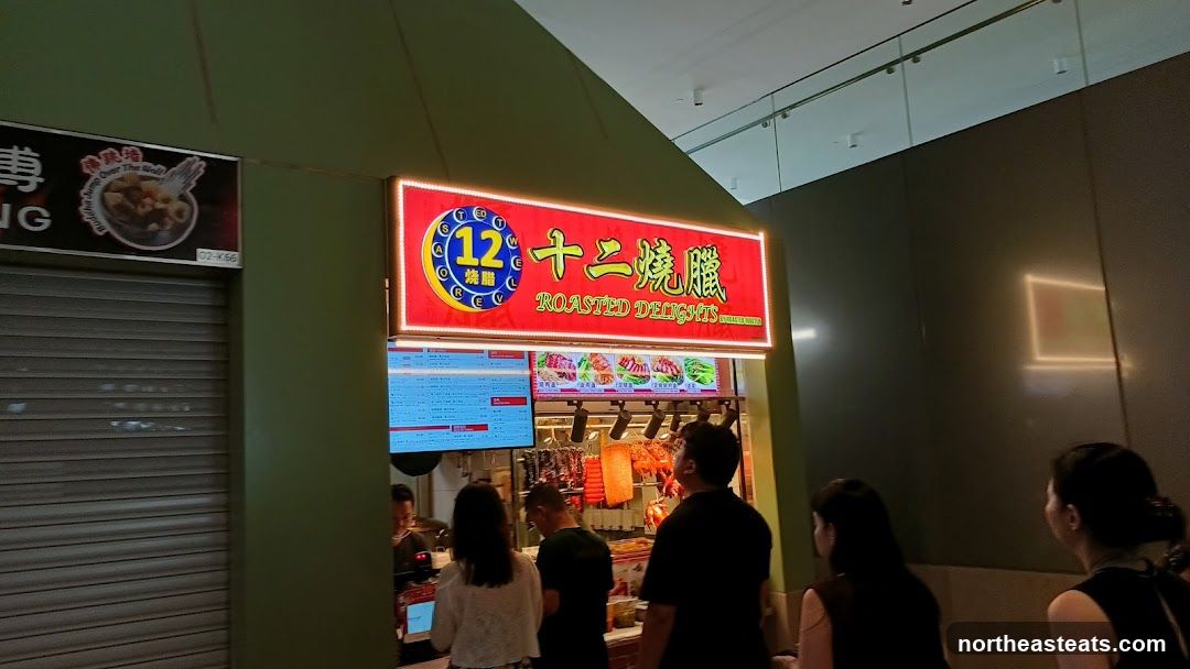A brightly lit sign for "Roasted Delights" is displayed above a food stall. Below the sign, a menu board is visible on the left, and images of roasted meats are displayed on the right. Several people are standing in front of the stall, looking at the menu and food. To the left of the stall, a closed metal shutter is visible.