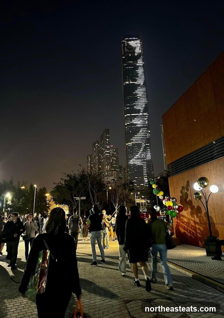 Nighttime cityscape with illuminated skyscraper and crowd