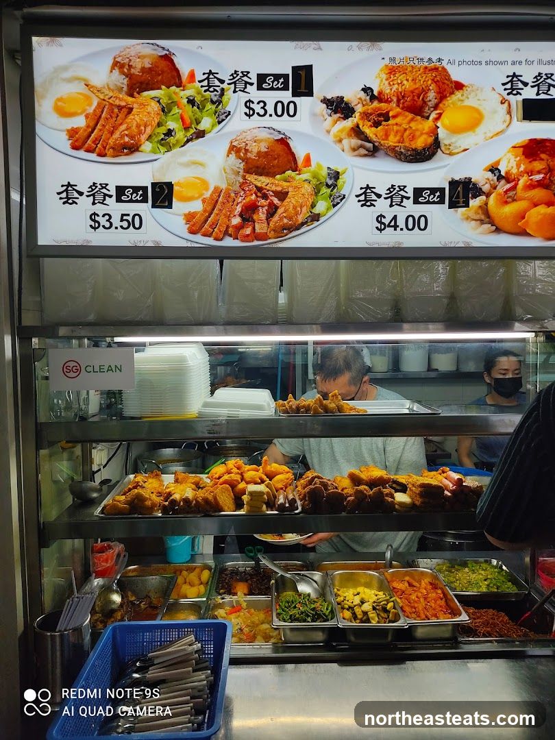 A menu board displaying various food sets with prices. Below the menu board, a display of prepared food items is visible.