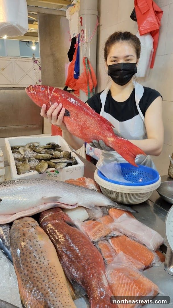 Fishmonger holding a large red fish