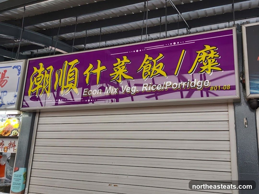 A closed stall with a large purple sign above a metal roller shutter. The sign has yellow Chinese characters and English text that reads "Econ Mix Veg. Rice/Porridge #01-08". To the left of the stall, a menu board displays images of food, including "Unagi Teriyaki $8.00".